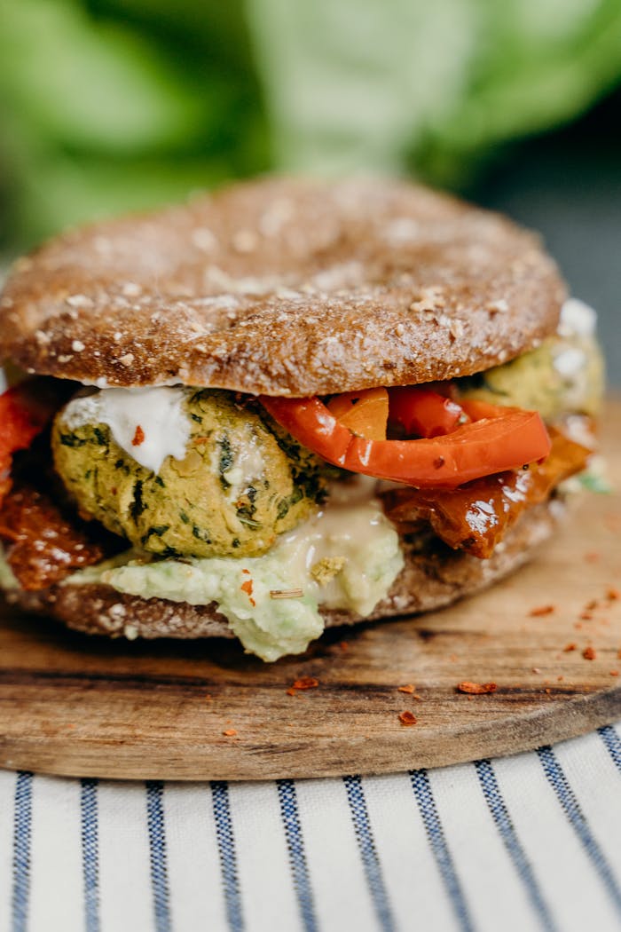 Savor a gourmet falafel sandwich with fresh veggies and sauce on a wooden board.
